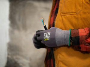 An electrician with work gloves holding a wire.