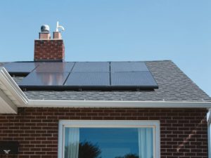 Vivint Solar - Solar Panels on roof of brick home with window and Adirondack chairs.