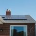 Vivint Solar - Solar Panels on roof of brick home with window and Adirondack chairs.